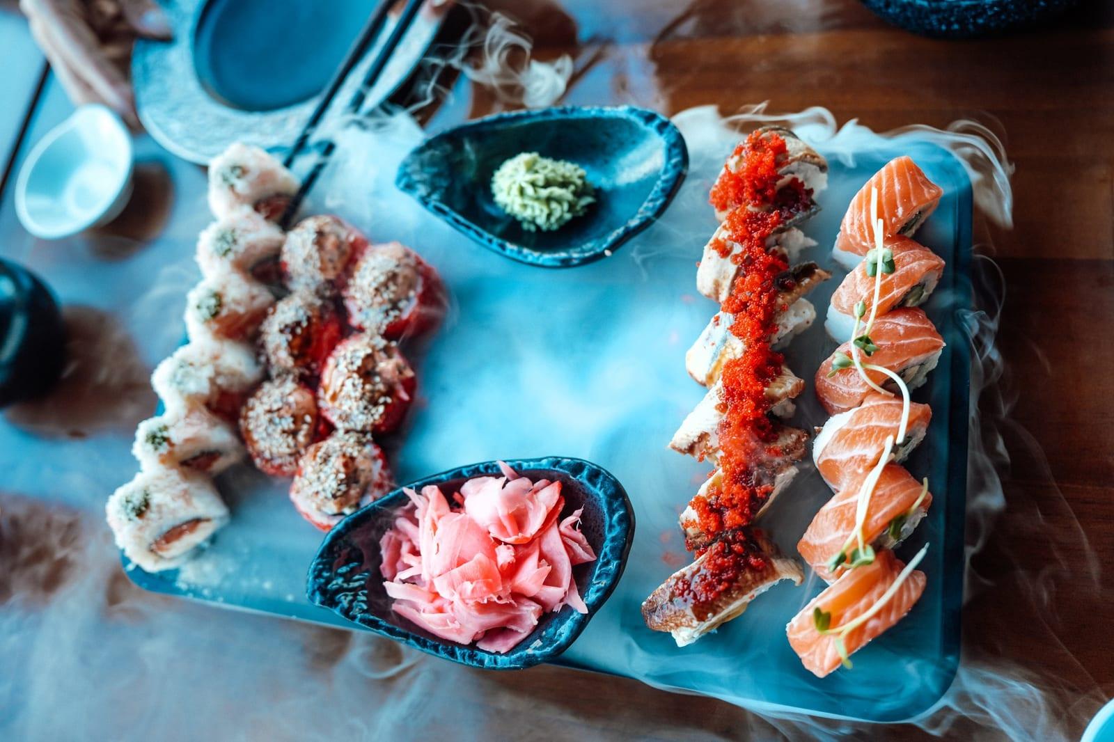 Sushi rolls on a smoking stone plate with wasabi and ginger