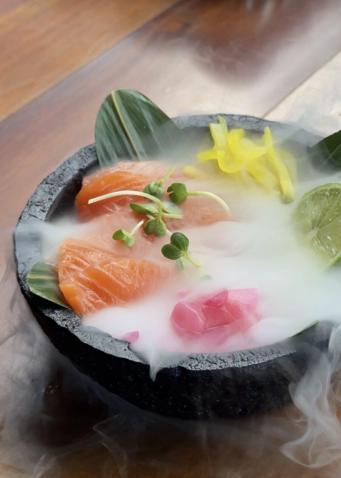 Close-up of smoking salmon sashimi with lime and pickled ginger